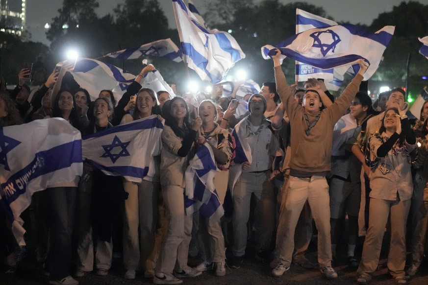 A group of Israelis celebrate as a helicopter carrying hostages released from the Gaza Strip lands on the helipad of the Schneider Children's Medical Center in Petah Tikva, Israel, on Sunday, November 26...