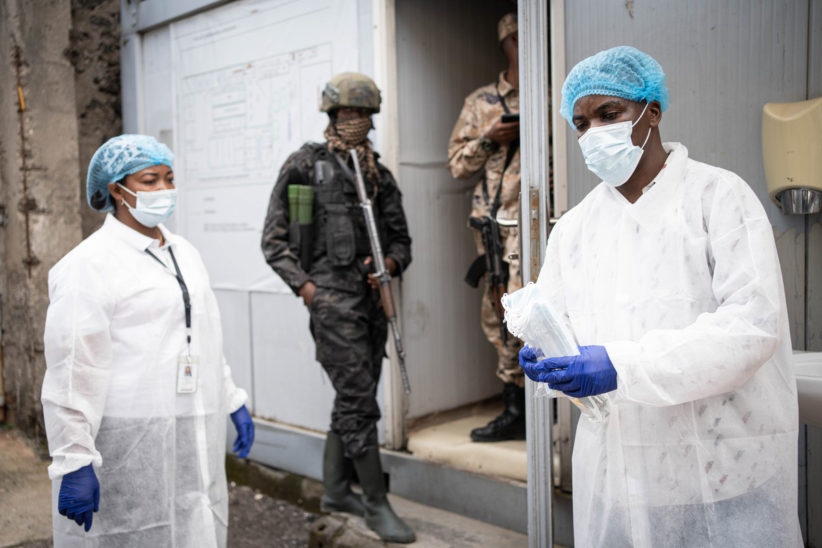 epa12973891 A staff in protective gown distributes facemaskes as a preventive measure against Ebola at the National Institute of Biomedical Resesarch (NIRB) in Goma, North Kivu, Democratic Republic of ...