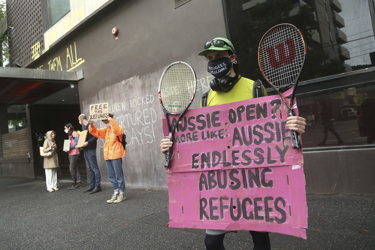 Protesters hold banners outside the Park Hotel calling for the release of refugees being detained inside in Melbourne, Australia, Saturday, Jan. 8, 2022. The world���s No. 1-ranked tennis player Novak ...