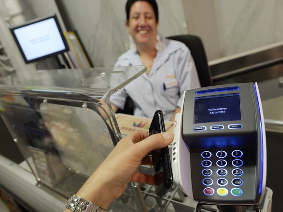 Eine Frau bezahlt mit dem Smartphone an der Kasse einer Coop Filiale in Zuerich am Dienstag, 1. Juli 2014. Mit &quot;Tapit&quot; kommt erstmals eine Smartphone App auf den Schweizer Markt, die das Bez ...