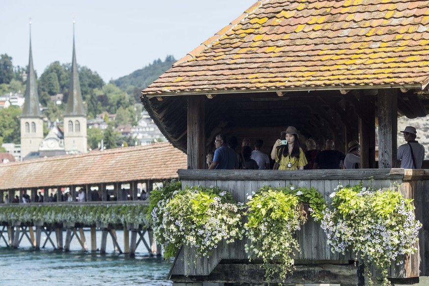 ARCHIV - ZUR TOURISMUSSTATISTIK UND DER ZUNAHME VON LOGIERNAECHTEN IN DER SCHWEIZ STELLEN WIR IHNEN DIESE BILDREPORTAGE ZUR VERFUEGUNG - A female Asian tourists on the Kapellbruecke bridge takes a pic ...