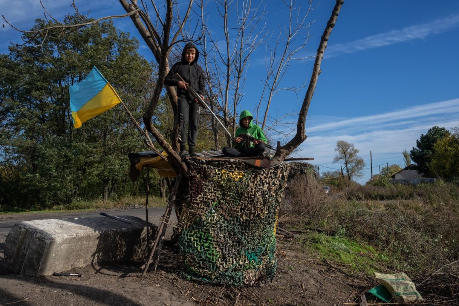 DUBOVE, UKRAINE - OCTOBER 19: Boys hold toy rifles as they pause while playing by the roadside on October 19, 2022 in Dubove, Kharkiv oblast, Ukraine. Russia's president Vladimir Putin today impo ...