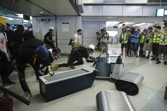 Demonstrators build a barricade during a protest at the Yuen Long MTR station in Hong Kong, Wednesday, Aug. 21, 2019. Hong Kong riot police faced off with protesters occupying a suburban train station ...