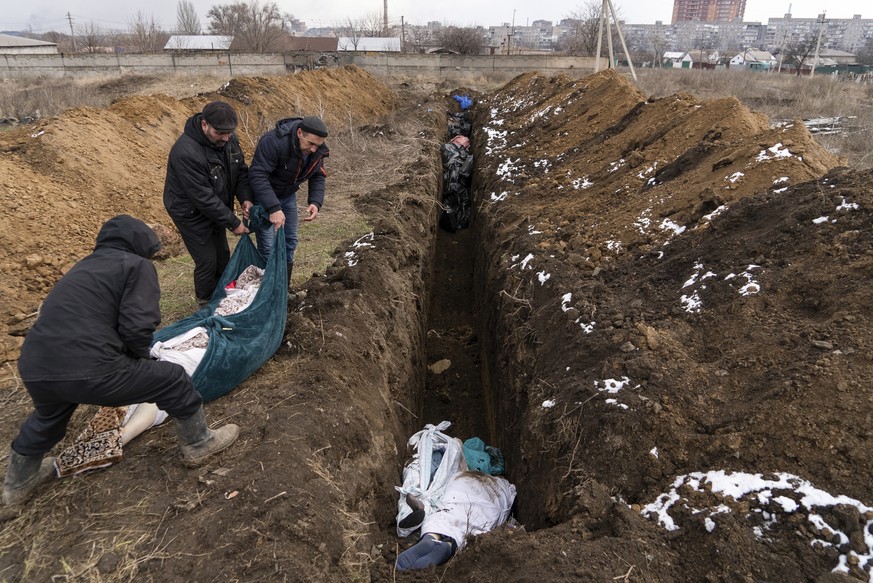 Dead bodies are placed into a mass grave on the outskirts of Mariupol, Ukraine, Wednesday, March 9, 2022, as people cannot bury their dead because of heavy shelling by Russian forces. (AP Photo/Mstysl ...