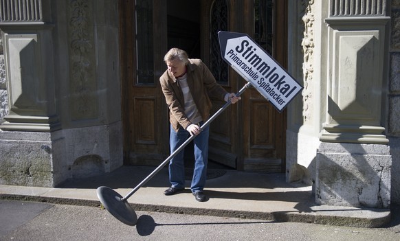 Dieter Gugerli rollt eine Hinweistafel vor das Abstimmungslokal &quot;Schulhaus Spitalacker&quot; des Kreises Breitenrain/Lorraine, am Sonntag, 18. Mai 2014, in Bern. Die Stimmbuerger des Kantons befi ...