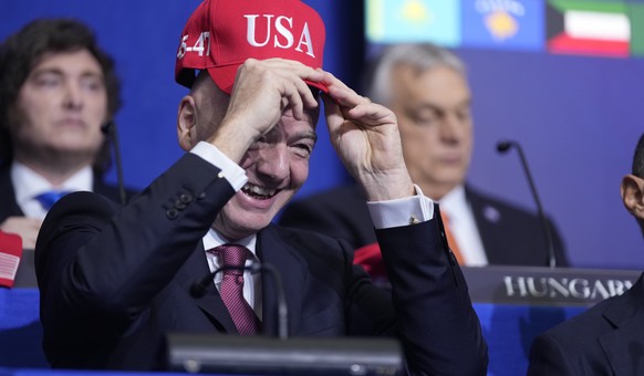 Giovanni Vincenzo Infantino, president of FIFA, tries out a USA hat during a Board of Peace meeting at the U.S. Institute of Peace, Thursday, Feb. 19, 2026, in Washington. (AP Photo/Mark Schiefelbein) ...