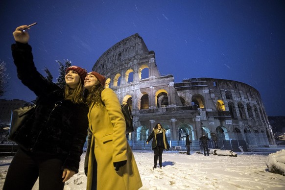 epa06565672 Tourists take a selfie in front of the Colosseum covered by snow during a snowfall in Rome, Italy, 26 February 2018. Schools and public offices were closed and snow-removal crews were in p ...