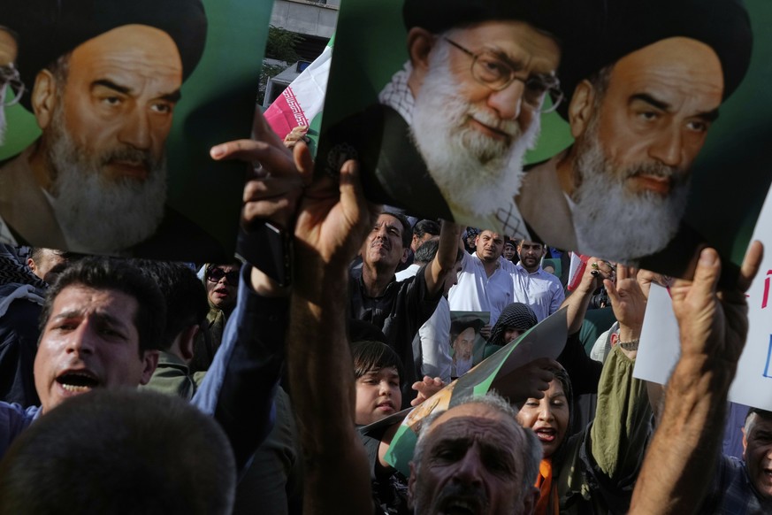 Iranian protesters hold up posters showing the Supreme Leader Ayatollah Ali Khamenei, center, and the late revolutionary founder Ayatollah Khomeini in a protest following the U.S. attacks on Iranian n ...