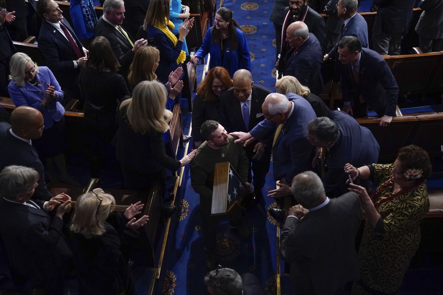 Lawmakers greet Ukrainian President Volodymyr Zelenskyy as he holds an American flag that was gifted to him by House Speaker Nancy Pelosi of Calif., as he leaves after addressing a joint meeting of Co ...