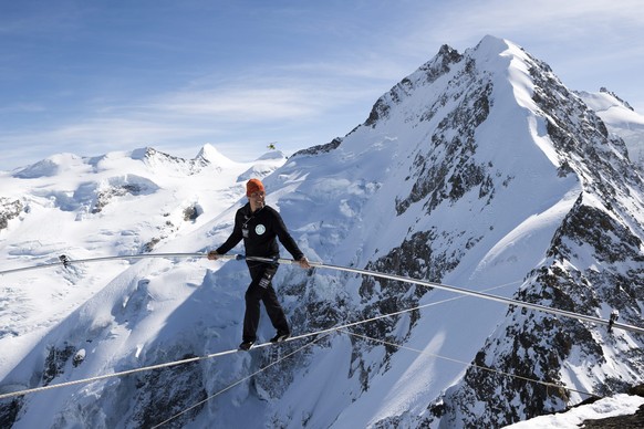 epa04671589 Swiss tightrope artist Freddy Nock walks on a rope towards Piz Prievlus, with the Piz Bernina and Biancograt ridge in the background, in Graubuenden, eastern Switzerland, 20 March 2015. He ...