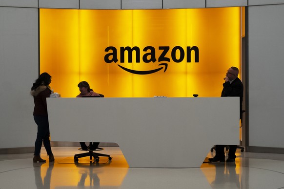 FILE - In this Thursday, Feb. 14, 2019, file photo, people stand in the lobby of Amazon offices in New York. Amid growing concern about the incentives that cities promised Amazon to land its new headq ...