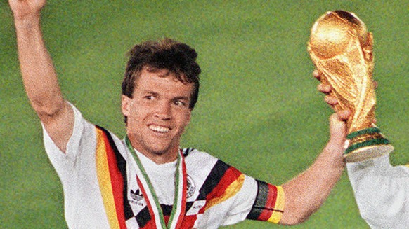 West German midfielder Lothar Matthaeus (L) and forward Pierre Littbarski celebrate with the World Cup trophy after their team beat the defending champions Argentina 1-0 on a penalty kick by defender  ...