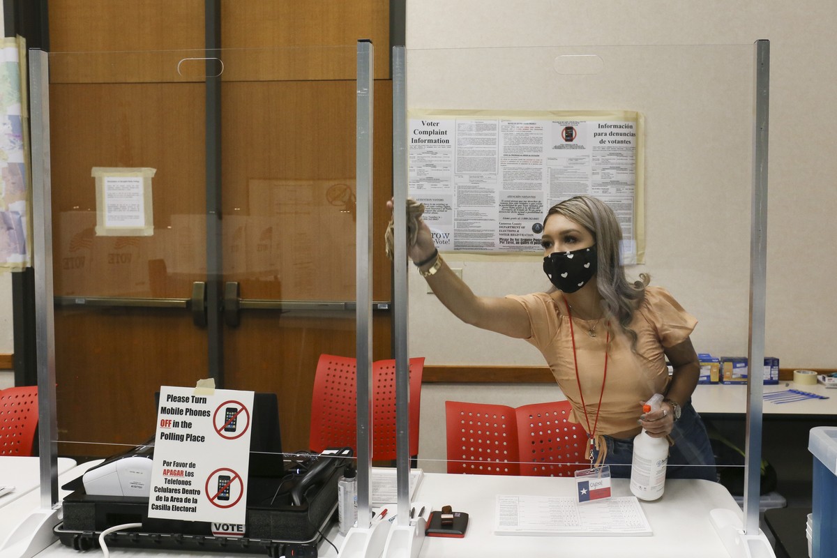 Cameron County early voting clerk Crystal Garcia sanitizes the plastic shields for the poll worker's station Thursday, Oct. 15, 2020, before the early voting polling location opens in Brownsville ...