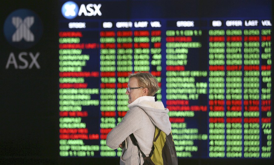 FILE - In this May 6, 2019, file photo, a woman looks at display boards at the Australian Stock Exchange in Sydney, Australia. Australia&#039;s central bank has cut its benchmark interest rate by a qu ...