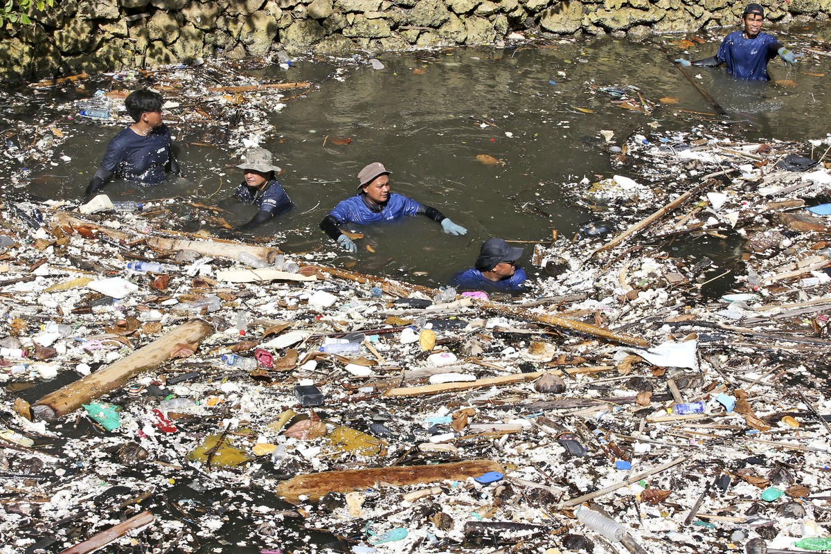 Environmental activists and volunteers pick up trash from a garbage-strewn river during a river clean up in Pecatu, Bali, Indonesia on Friday, March 22, 2024. (AP Photo/Firdia Lisnawati)