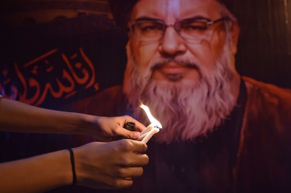 epa11631212 A protester lights candles in front of the pictures of late Hezbollah leader Hassan Nasrallah, during an anti-Israel protest following the death of Hezbollah leader Nasrallah, in Karachi,  ...