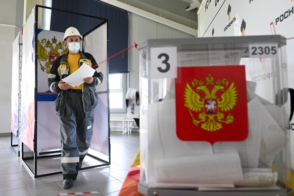 An oil worker holds his ballot as he leaves a voting booth during an early voting at the shift residential complex for oil production of Rosneft oil company in Uvat district of Tyumen region, 1891 km, ...