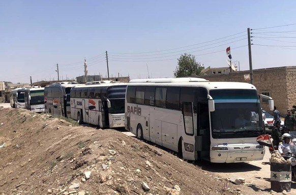 In this photo released by the Syrian official news agency SANA, buses arrive in Tel el-Eis, the crossing between Aleppo and Idlib provinces, Syria, Wednesday, July 18, 2018. About 7,000 Syrians were e ...