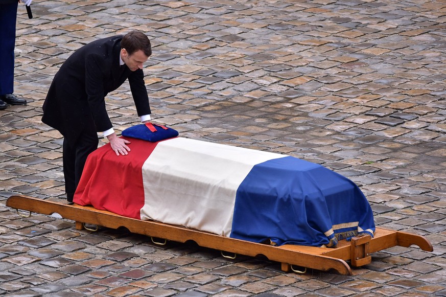 epa06634002 French President Emmanuel Macron stands in front of the flag-draped coffin of the Gendarme Lieutenant-Colonel Arnaud Beltrame during a solemn funeral ceremony, in the courtyard of the Inva ...