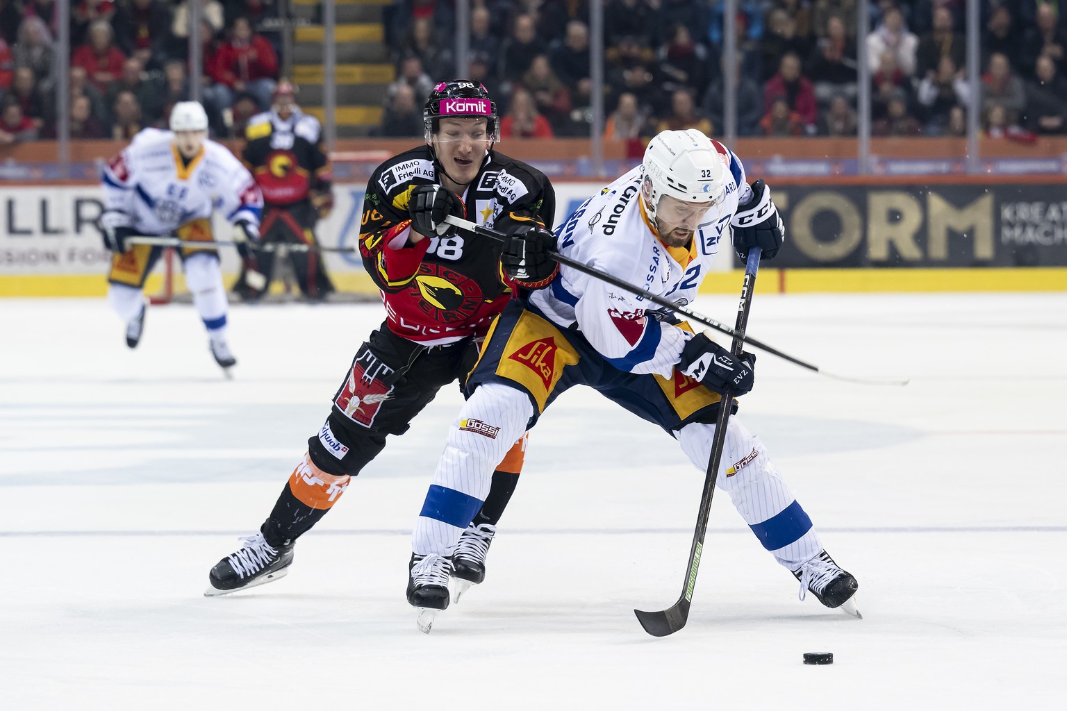 Berns Benjamin Baumgartner, links, und Zugs Lukas Bengtsson, rechts, kaempfen um den Puck, im zweiten Eishockey Playoff Viertelfinal Spiel der National League zwischen dem SC Bern und dem EV Zug, am D ...