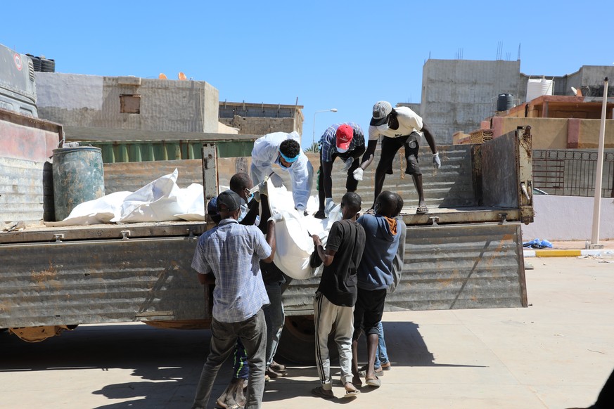 epa10859581 Rescue workers transport body bags with the remains of victims of the floods, which washed up ashore from the sea, outside the hospital of Derna, Eastern Libya, 13 September 2023, after St ...