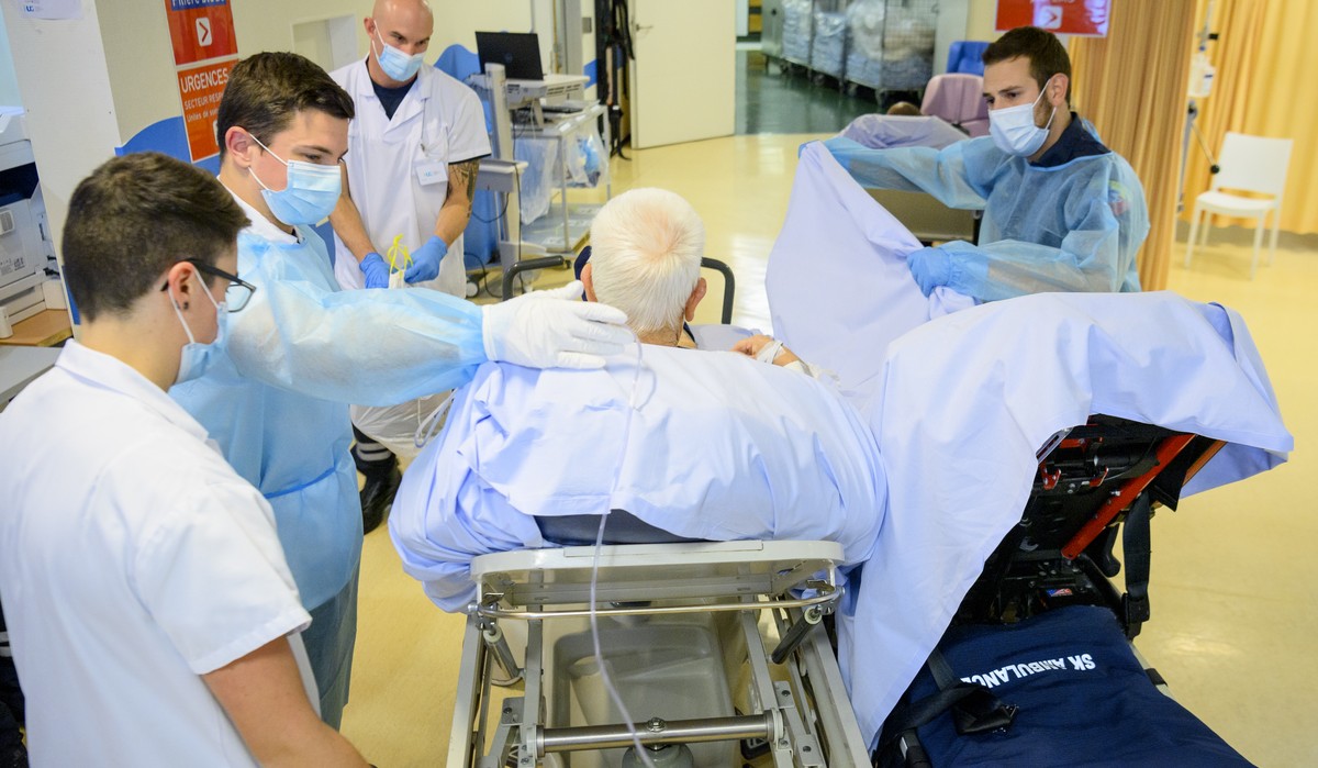 Geneva's aspiring firefighters help paramedics taking care of a patient in the first aid department of Geneva University Hospitals (HUG), during the coronavirus disease (COVID-19) outbreak, in Ge ...