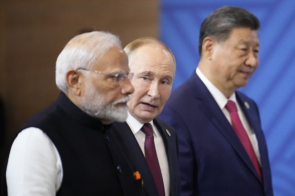 From left, Indian Prime Minister Narendra Modi, Russian President Vladimir Putin and Chinese President Xi Jinping attend a family photo ceremony prior to the BRICS Summit plenary session in Kazan, Rus ...