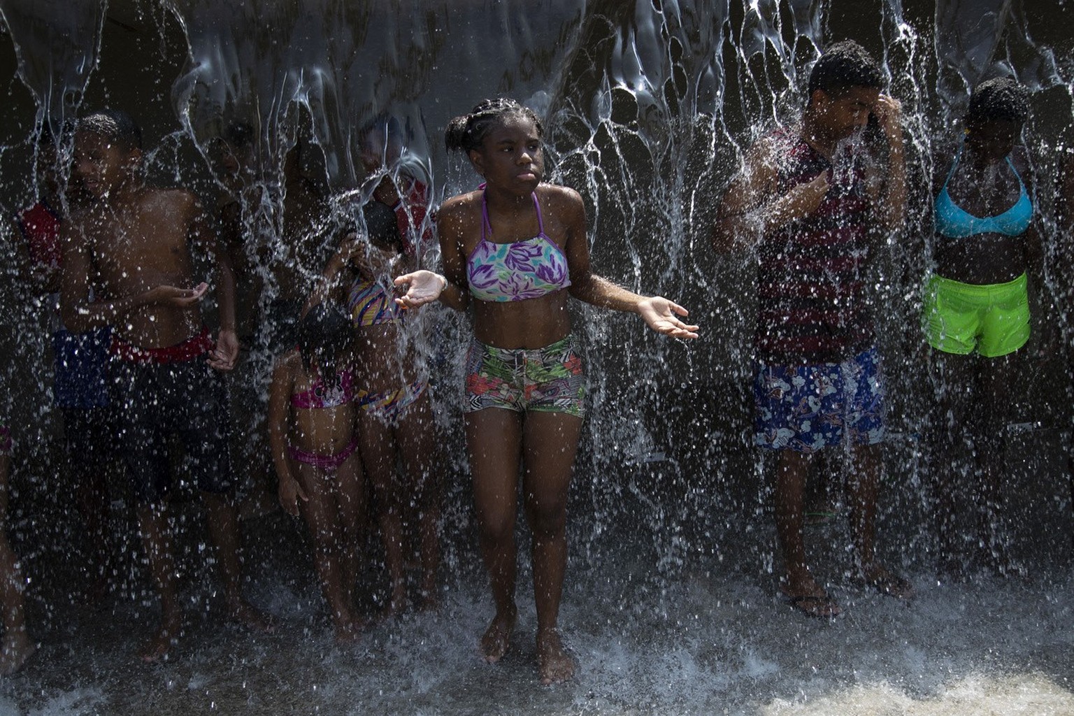 People cool off in a water fountain at Madureira Park amid a heat wave in Rio de Janeiro, Brazil, Wednesday, Nov. 15, 2023. (AP Photo/Bruna Prado)