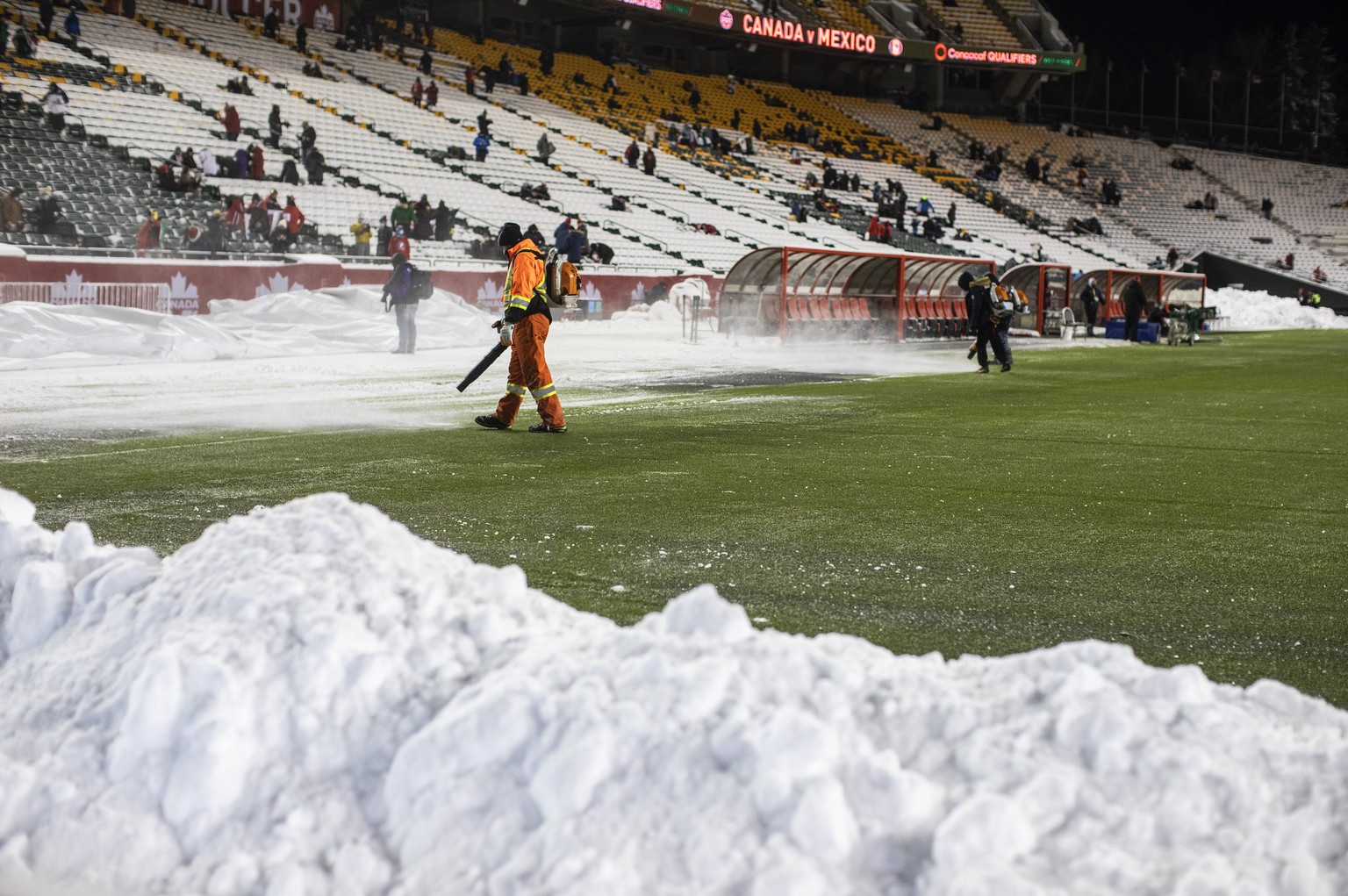 Crews clean snow off the field before a FIFA World Cup qualifying soccer match between Canada and Mexico, Tuesday, Nov. 16, 2021, in Edmonton, Alberta. (Jason Franson/The Canadian Press via AP)