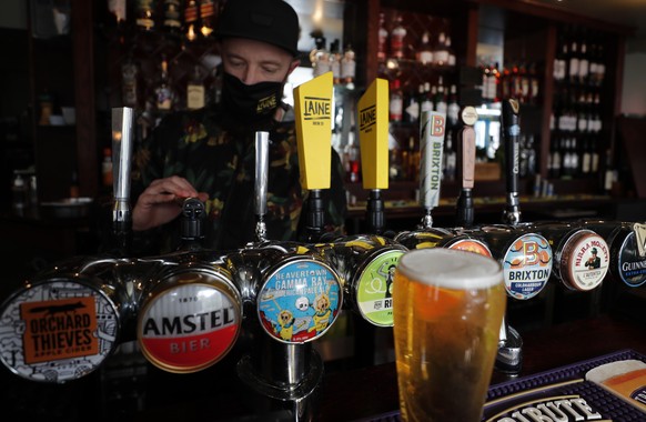 A barman draughts beer in the Black Lion pub in Hammersmith in London, Monday, May 17, 2021. Drinks were raised in toasts and reunited friends hugged each other as thousands of U.K. pubs and restauran ...