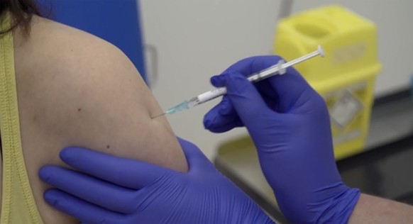 Screen grab taken from video issued by Britain's Oxford University, showing a person being injected as part of the first human trials in the UK to test a potential coronavirus vaccine, untaken by Oxford University in England, Thursday April 23, 2020.  Two volunteers have received the first vaccine trial against the COVID-19 Coronavirus on Thursday. (Oxford University Pool via AP)