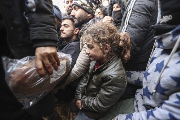 epa09579113 Asylum-seekers, refugees and migrants, gather to receive humanitarian aid distributed by Belarusian military at a camp at the Belarus-Polish border in the Grodno region, not far from the c ...