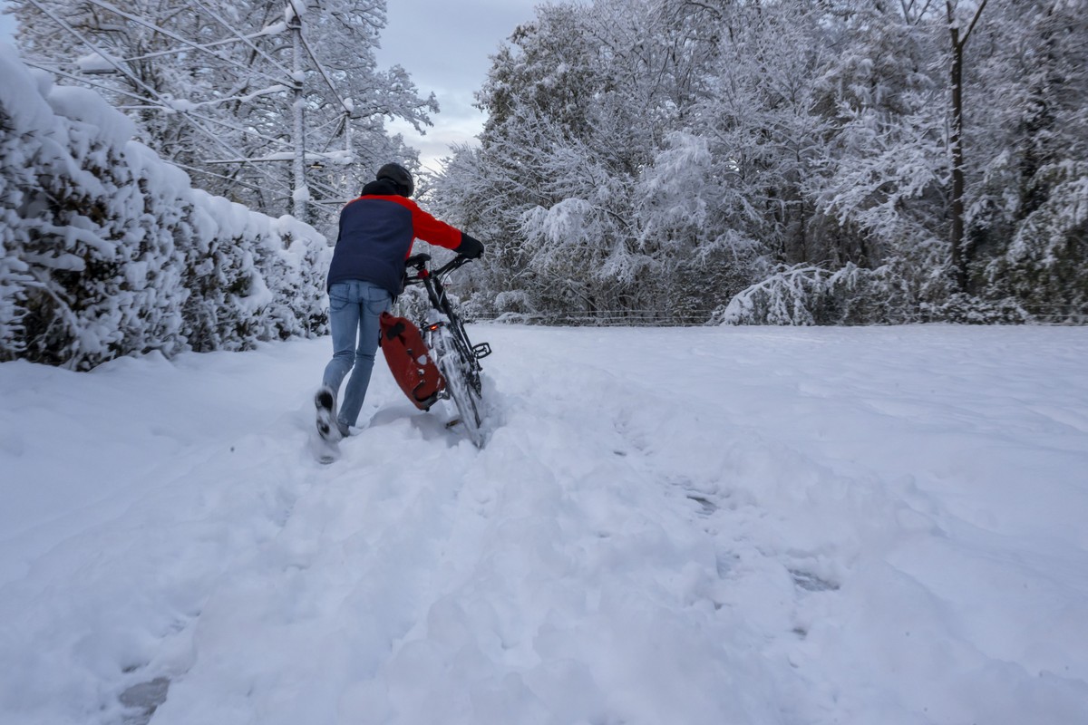 Ein junger Mann schiebt sein Fahrrad durch den Schnee auf einem Weg im Waldgebiet Lange Erlen in Basel, am Freitag, 22. November 2024. (KEYSTONE/Georgios Kefalas)