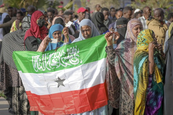 A woman displays the Somaliland flag as people queue to cast their votes during the 2024 Somaliland presidential election at a polling station in Hargeisa, Somaliland, Wednesday, Nov. 13,2024. (AP Pho ...