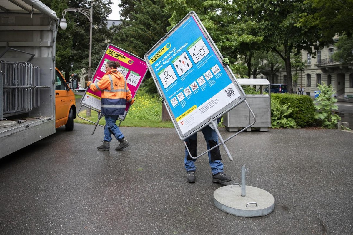 David Goncalves, vorne verdeckt, und Roger Mundwiler, hinten, Mitarbeiter des Tiefbauamts der Stadt Bern, installieren die neuen blauen BAG-Plakate mit Verhaltensregeln im Umgang mit dem Coronavirus u ...