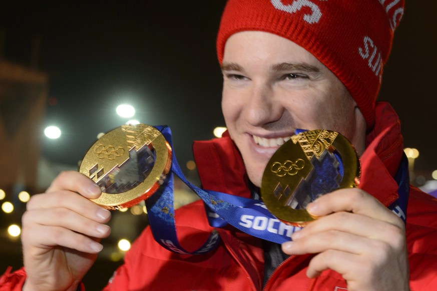 Cross country skiing 15km classic and skiathlon gold medalist Switzerland&#039;s Dario Cologna poses with his two gold medals in front of the Olympic Flame on the top of the Olympic cauldron after the ...