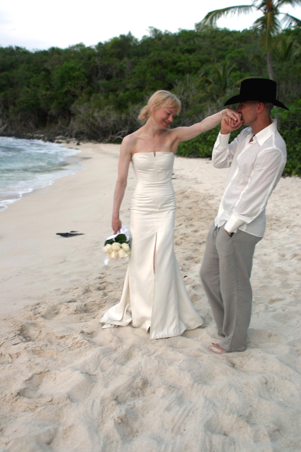 This photo from Carolina Herrera shows country music star Kenny Chesney kissing the hand of his bride, actress Renee Zellweger, wearing her Carolina Herrera designed wedding dress, on the beach in Cru ...