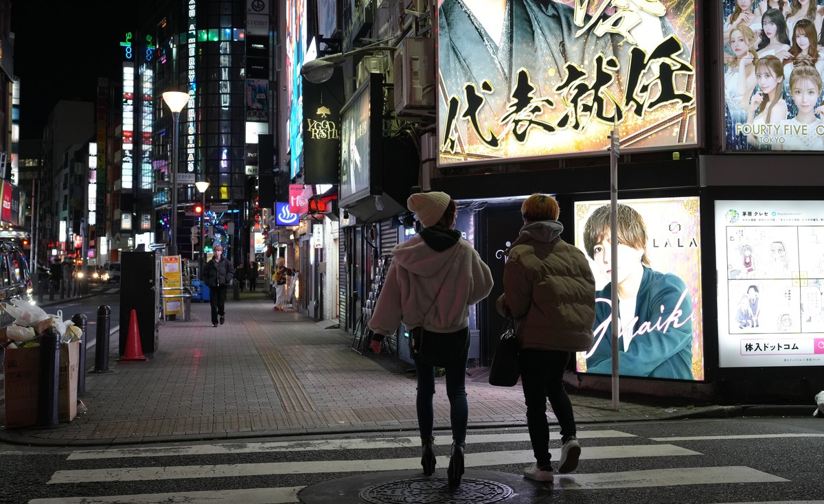 epa11024109 Pedestrians walk past a billboard of a 'Host Club' at Kabukicho district, Shinjuku in Tokyo, Japan, 06 December 2023 (issued 12 December 2023). A worrying trend of vulnerable you ...