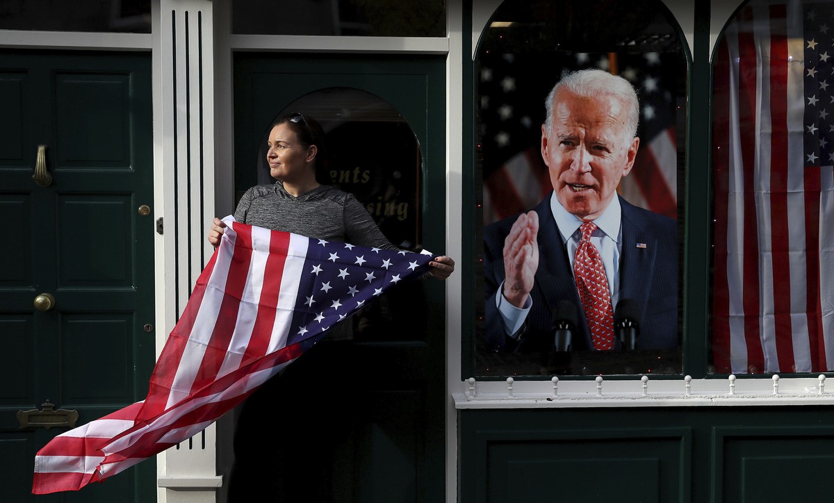 Catherine Hallahan, owner of Hallihan's barbers holds a US flag, as residents begin celebrations in the ancestral home of Joe Biden in anticipation of the results of the US election, in Ballina,  ...