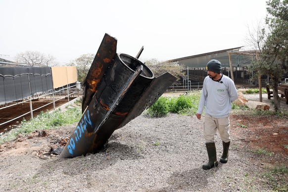 epaselect epa12868586 A Thai agricultural worker examines the tail of an Iranian ballistic missile that hit near a cow barn in the Israeli settlement of Shadmot Mehola, in West Bank, 04 April 2026. Ir ...