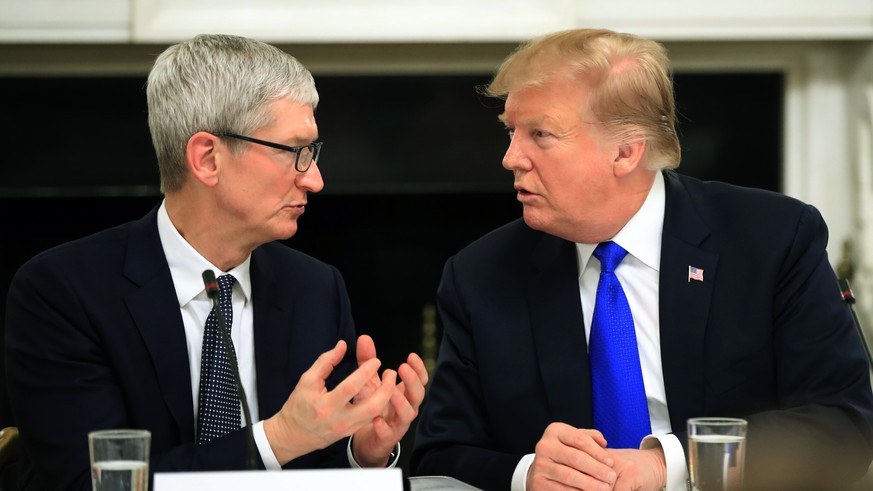 FILE - In this Wednesday, March 6, 2019 file photo, President Donald Trump talks to Apple Inc. CEO Tim Cook during the American Workforce Policy Advisory Board's first meeting in the State Dining ...