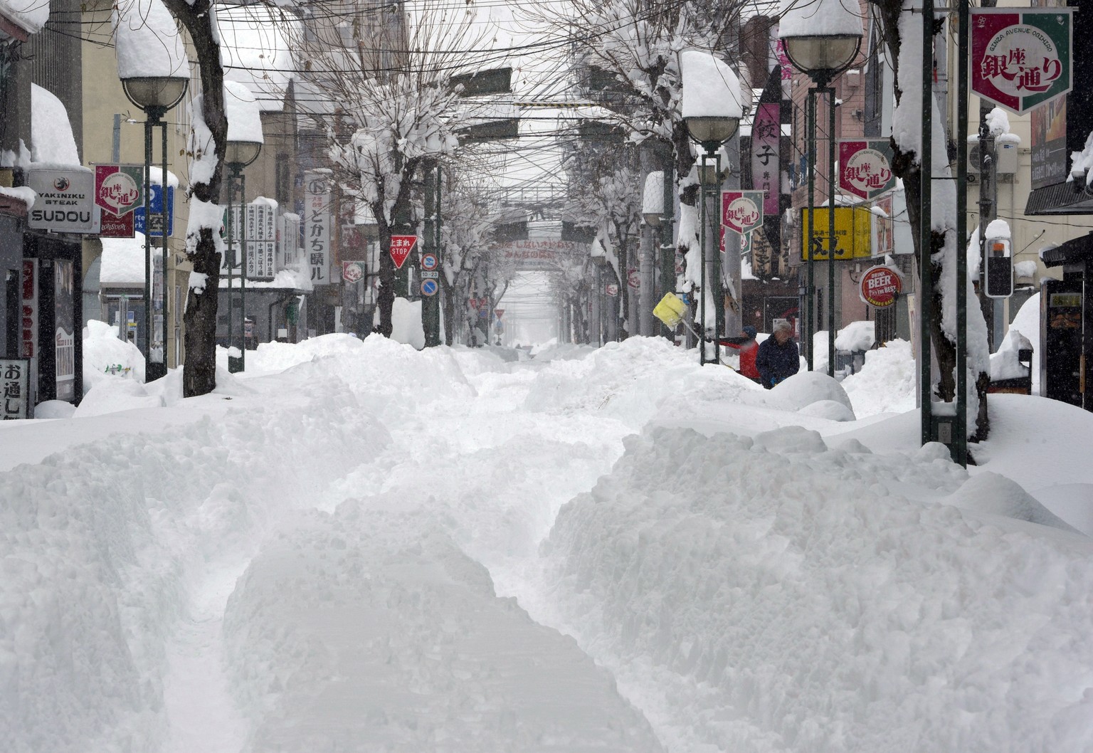 epa11875686 People walk in a street covered with snow following heavy snowfall in Obihiro, Hokkaido, northern Japan, 04 February 2025 (issued 05 February 2025). On 05 February 2025, the coldest air of ...