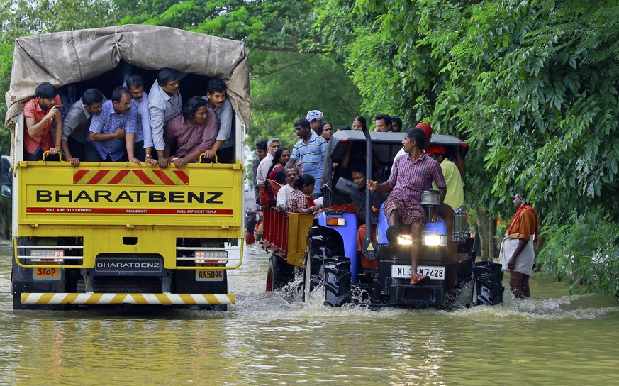 Flood affected people are rescued in a tractor, right as volunteers go for rescue work in a truck, left, at Kainakary in Alappuzha district, Kerala state, India, Friday, Aug. 17, 2018. Rescuers used h ...