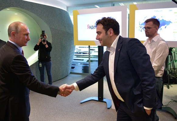 Russian President Vladimir Putin, left, shakes hands with Tigran Khudaverdyan, manager of Yandex.Taxi project, as he visits Russia's largest internet search engine Yandex headquarters in Moscow, Russi ...