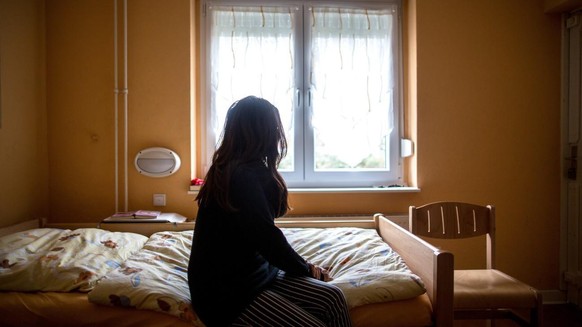 ARCHIV - 12.11.2015, Nordrhein-Westfalen, Herne: Eine Frau sitzt in einem Frauenhaus auf einem Bett. Im Jahr 2019 haben Tausende von Gewalt betroffene Frauen und Kinder in Frauenhäusern Schutz gesucht ...