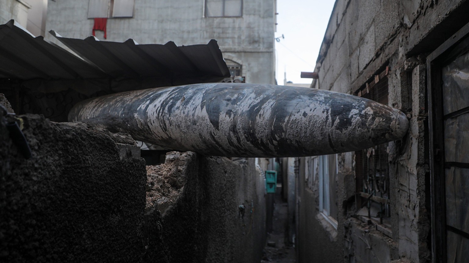 epa11085712 During Israeli operations in the southern Gaza Strip, January 17, 2024, an unexploded rocket is seen stuck between two houses of the Al Nusairat refugee camp.  More than 24,400 Palestinians and…