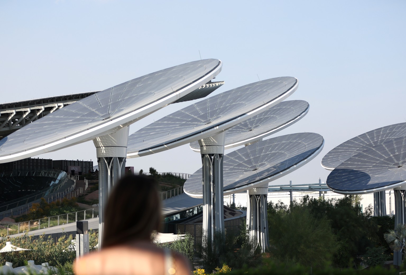 epa11018997 A woman stands in front of the solar energy trees at the Sustainability Pavilion at the Green Zone as part of the venue of the 2023 United Nations Climate Change Conference (COP28) in Duba ...