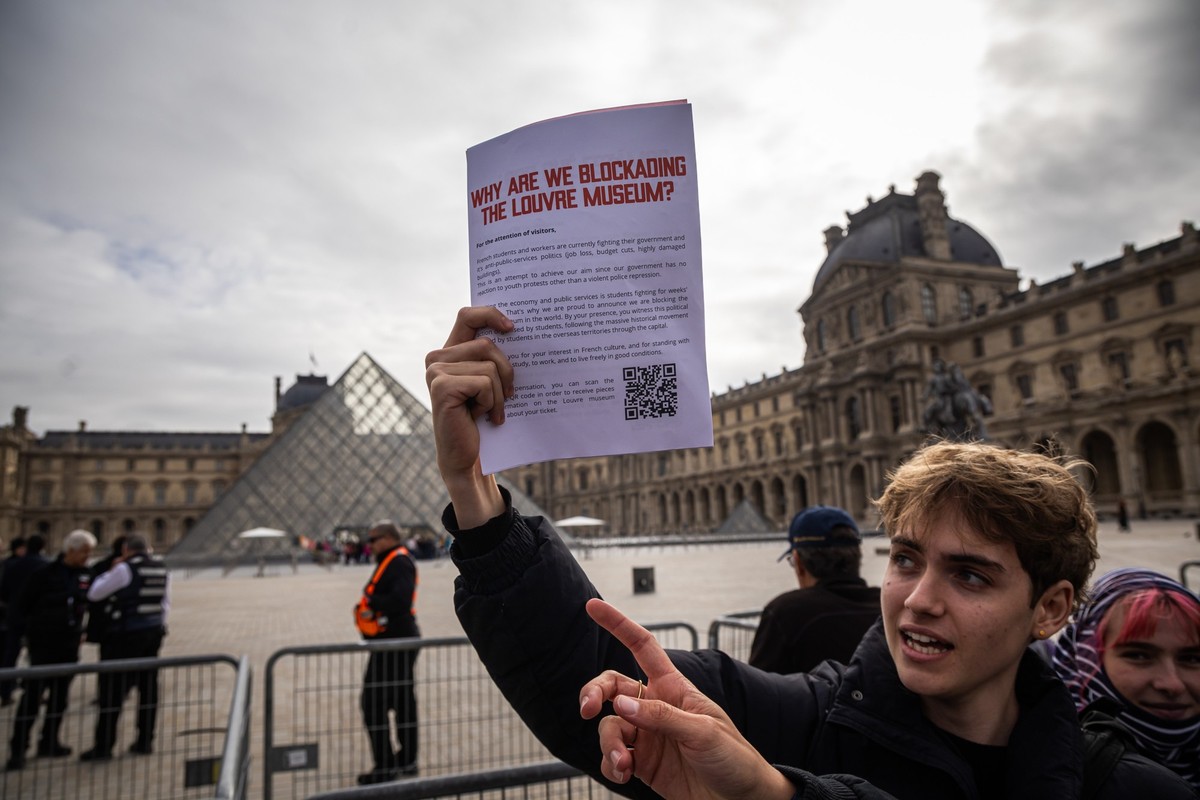epa13315305 A protester holds a sign reading 'Why are we blockading the Louvre Museum?' as students and union members block an entrance to the museum to express their 'support' for ...