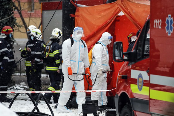 Men wearing protective outfits wait to disinfect firefighters who tackled a fire at a building in the Matei Bals hospital compound in Bucharest, Romania, Friday, Jan. 29, 2021. A fire early Friday at  ...