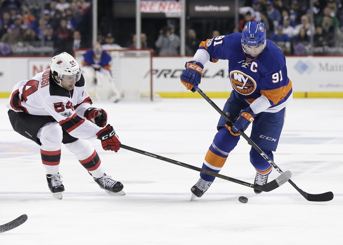 New Jersey Devils' Joseph Blandisi (64) and New York Islanders' John Tavares (91) fight for the puck during the second period of an NHL hockey game Friday, March 31, 2017, in New York. (AP P ...